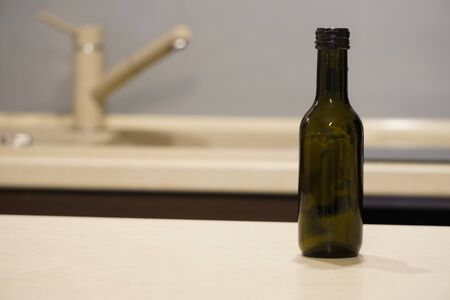 a small dark glass wine bottle stands on the table against the kitchen background. decor, home decoration.の写真素材