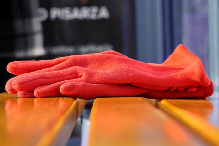 red women's gloves forgotten on a bench or at a bus stop on warm Sunny day. warehouse or lost and...