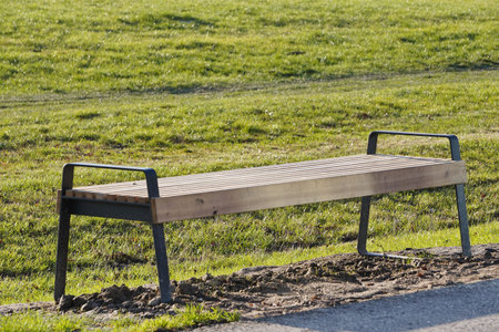 modern wooden empty bench by the road in the Park on a Sunny day. place to relax while walking.