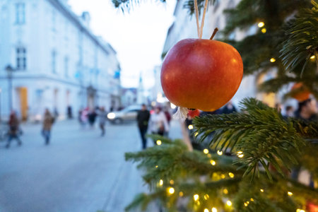 Christmas tree decoration with apples and luminous garland, handmade. cobbled streets of Krakow are ready for Christmas and new year. people are blurred in the backgroundの写真素材