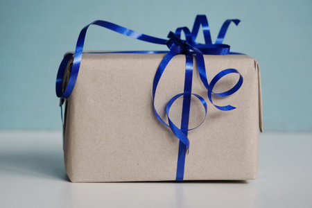 box in gift craft packaging with blue ribbon and a bow on turquoise or green background. gifts for...