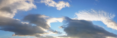 large white fluffy sun-lit clouds against a blue sky. illuminated by direct light from sun....