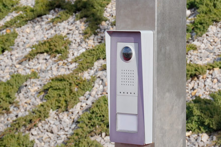 Gray metal button on post for exiting the fenced area against the background of greenery, security...