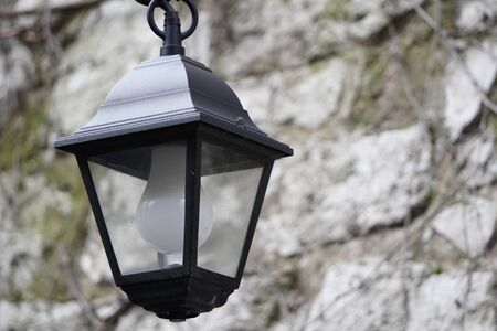 Old-style street lamp with led light, grey stone wall on the backgroundの写真素材