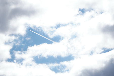 White light fluffy clouds in blue sky with a solar flare.