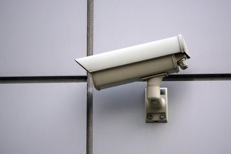Camera CCTV on the facade of a modern office building on the street, security in the city. Covert...