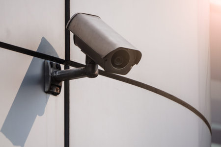 Camera CCTV on the facade of a modern office building on the street, security in the city. Covert...