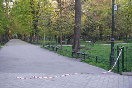 Poland, Cracow 20.04.20: Removing restrictions on visiting parks and forests, and Plenty Gardens during quarantine and coronavirus pandemic. barrier tape is torn and lies on path. Social distancingのeditorial素材