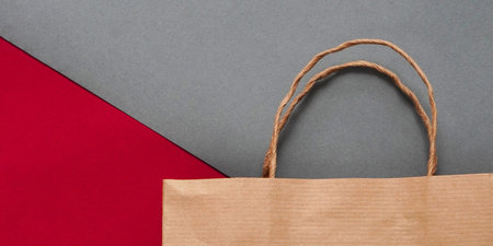 Top view of empty craft paper bag on maroon background. Flat lay on maroon background, zero waste....