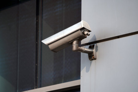 Camera CCTV on the facade of a modern office building on the street, security in the city. Covert...
