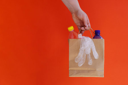 plastic bottles of transparent and blue color in craft bag, transparent disposable gloves on red...