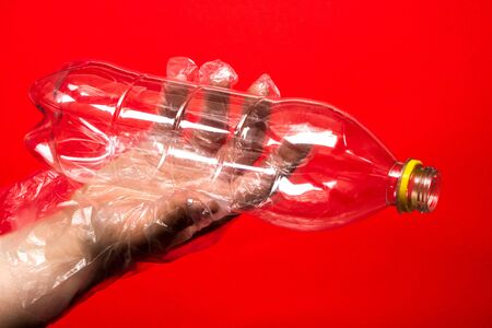 Hand in plastic or rubber disposable glove holds plastic transparent bottle of carbonated drink. Zero waste, sorting garbage,reusable containers.ecology environment protection and coronavirus concept.の写真素材