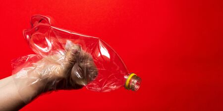 Hand in plastic or rubber disposable glove holds plastic transparent bottle of carbonated drink. Zero waste, sorting garbage,reusable containers.ecology environment protection and coronavirus concept.の写真素材
