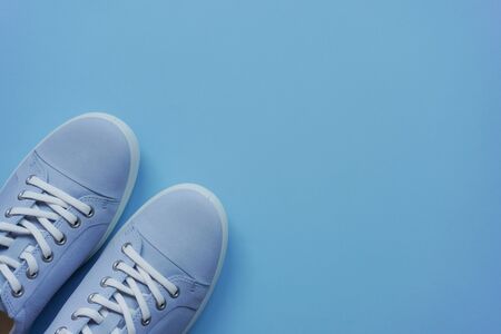 Light blue sneakers with white laces and white sole on a blue flat lay background. Copy space. Lifestyle, outdoor shoes for walking. Casual unisexの写真素材