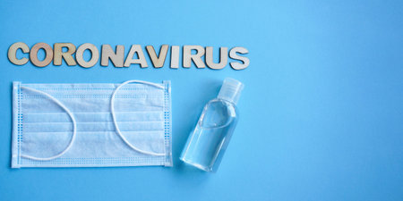 Antiseptic and medical mask, Inscription coronavirus is made of wooden letters laid out on blue...