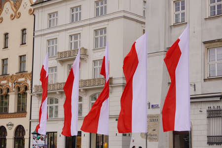 Polish red and white flags in the Old town in front of building on a Sunny day.1 of May, November 11, flag or independence or labor day. Government holiday - Poland, Krakow 03.05.2020のeditorial素材