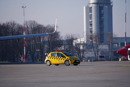 Krakow, Poland 20.12.2019: yellow Toyota Yaris airport technical service car is driving along the runway at the airport. organization of traffic on runway, airport control service.のeditorial素材