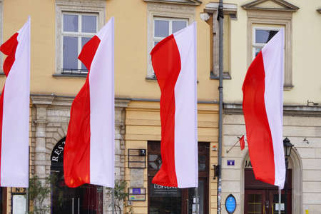 Polish red and white flags in the Old town in front of building on a Sunny day.1 of May, November 11, flag or independence or labor day. Government holiday - Poland, Krakow 03.05.2020のeditorial素材