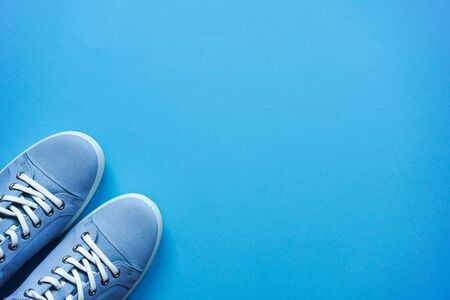 Light blue sneakers with white laces and white sole on a blue flat lay background. Copy space. Lifestyle, outdoor shoes for walking. Casual unisexの写真素材