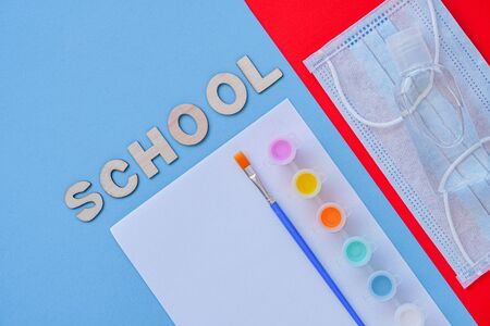 Study flatlay concept. Education supplies-brush, paint, medical mask and sanitizer on blue,white and red background,back to school or kindergarten. summertime, creativity and learn backgroundの写真素材