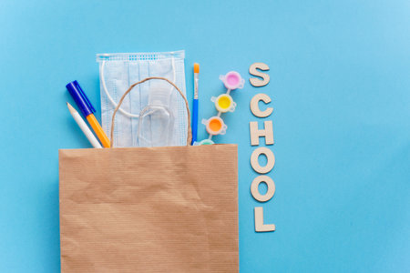 Study flatly. Education supplies-pencil,pen,brush, paint, medical mask and sanitizer paint on blue...