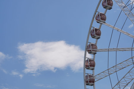 Modern white Ferris wheel against blue sky with clouds, Attraction for children and tourists, top...