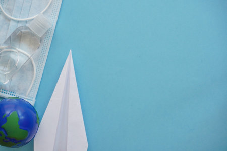 Top view planet earth,mask, sanitizer, paper airplane on blue. Relax on coronavirus.Summer flatly,...