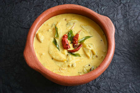 Yellow mango curry or Mampazha Pulissery sweet and sour dish for Onam Sadhya or Sadya Kerala India. organic raw ripe mango, coconut milk, seasoned with curry leaves, mustard, Indian red Kashmir chilliの写真素材