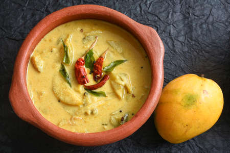 Yellow mango curry or Mampazha Pulissery sweet and sour dish for Onam Sadhya or Sadya Kerala India. organic raw ripe mango, coconut milk, seasoned with curry leaves, mustard, Indian red Kashmir chilliの写真素材