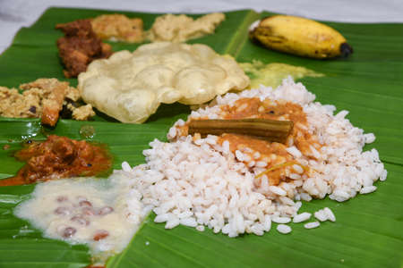 Onam Sadhya, traditional Indian lunch boiled rice served on green banana leaf with many spicy hot curries and lots of sweet dessert for Kerala harvest festival in India.の写真素材