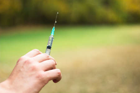 Man addicted with syringe injecting, outdoorsの写真素材