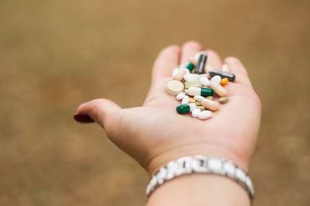 Woman's hand holding blister packs, nature bokeh backgroundの写真素材
