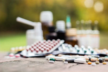 Colorful pills and capsules on wooden table, nature bokeh backgroundの写真素材