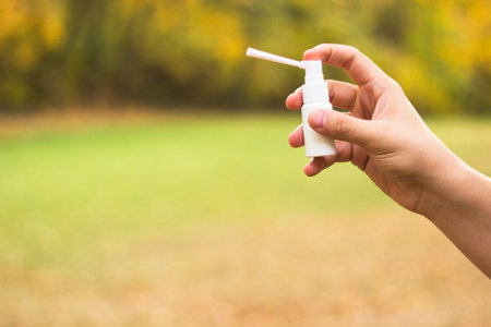 Throat spray in man hand, outdoors, nature background