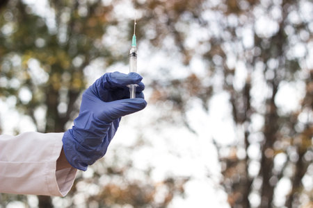 Woman doctor holding medical syringe. Vaccine in a bottle withdrawn with syringeの写真素材