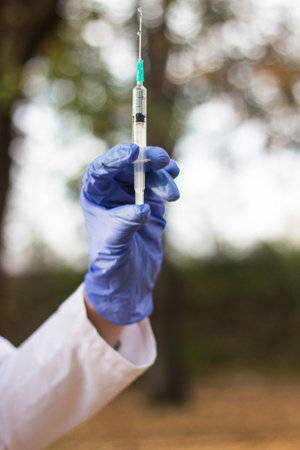Woman doctor holding medical syringe. Vaccine in a bottle withdrawn with syringeの写真素材