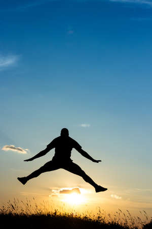 Young male jumping at sunset, silhouette in the natureの写真素材
