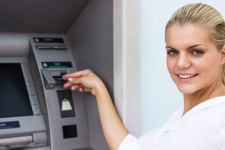 Beautiful businesswoman withdrawing money from credit card at ATMの写真素材
