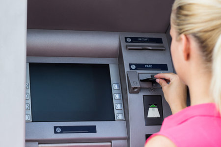 Beautiful businesswoman withdrawing money from credit card at ATM