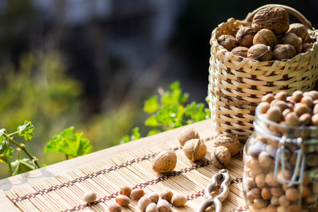 Walnuts and Hazelnuts in a wicker basket on old wooden tableの写真素材