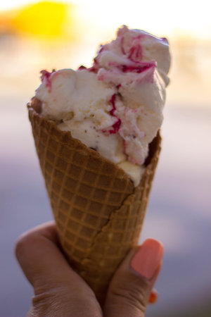Woman hand holding an ice cream cone. Bokeh backgroundの写真素材