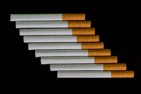 Cigarettes arranged in a row, black background