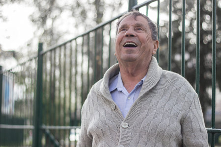 Portrait of happy senior man smiling, in the public park, outdoors.. Old man relaxing outdoors and...