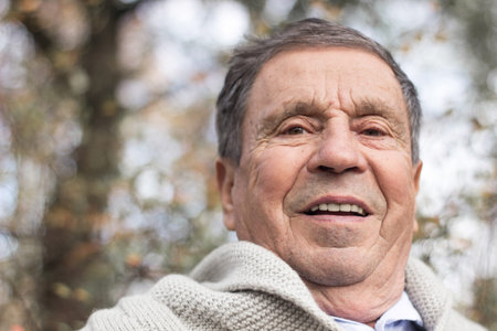 Portrait of happy senior man smiling, in the public park, outdoors. Old man relaxing outdoors and...