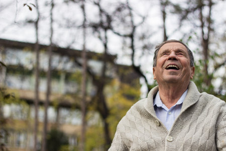 Portrait of happy senior man smiling, in the public park, outdoors. Old man relaxing outdoors and...