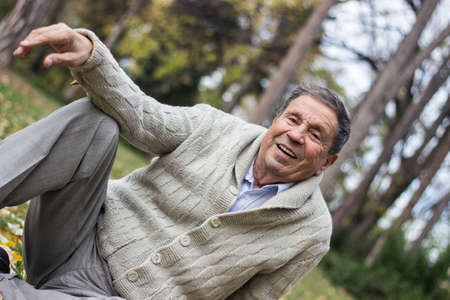 Portrait of happy senior man smiling, in the public park, outdoors. Old man relaxing outdoors and looking away. Portrait of elderly man enjoying retirementの写真素材