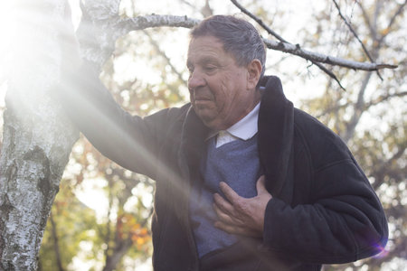 Senior man suffering from heart attack, outdoors. Elderly man having chest pains or heart attack in...