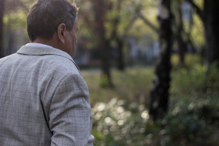 Senior man walking, hands clasped. Senior man walking and relaxing in park. Walking away, relaxing, rear viewの写真素材