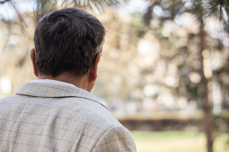 Senior man walking, hands clasped. Senior man walking and relaxing in park. Walking away, relaxing,...