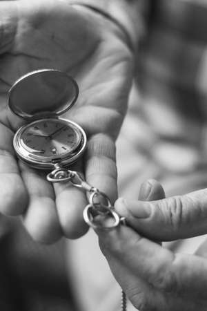 Old hands hold an antique pocket watchの写真素材